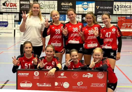 Jeugdploeg van Divo Ingelmunster achter het bord met de clubsponsors