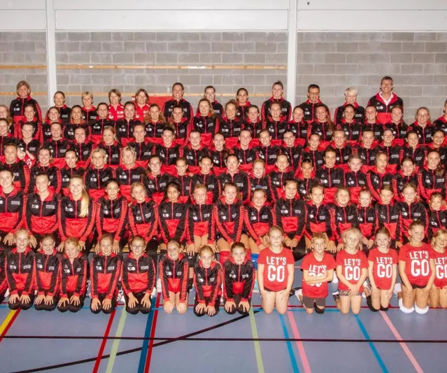 Groepsfoto van alle speelsters, trainers en vrijwilligers van Divo Ingelmunster in de sporthal